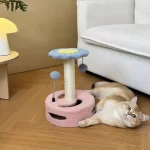 A playful kitten batting at the hanging toy ball on the cat scratching post.